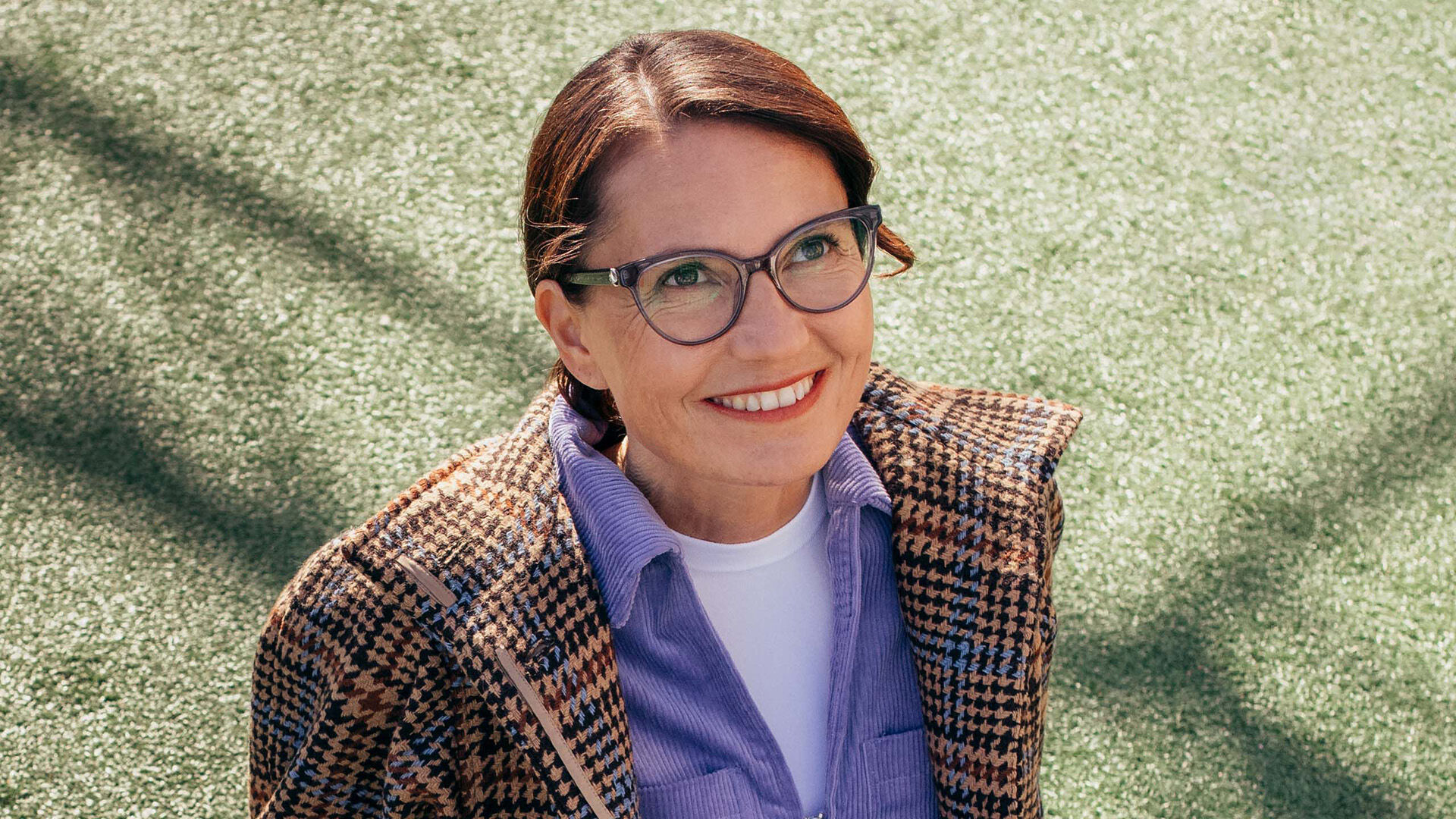 Ik&auml;n&auml;k&ouml;inen nainen istuu maassa silm&auml;lasit kasvoillaan taivaalle katsellen